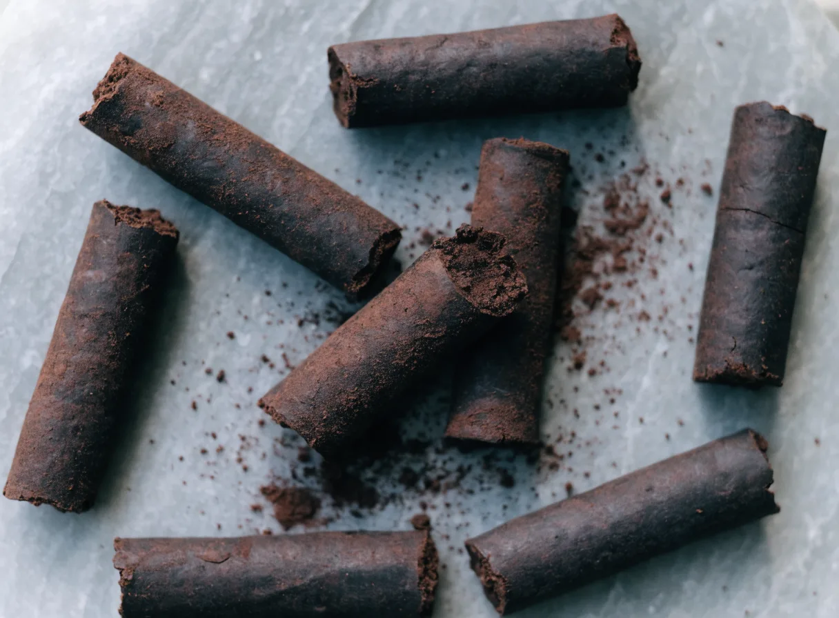 Roasted cocoa sticks, hand-rolled cylinders of ground cacao with one snapped open to show the fudgy interior
