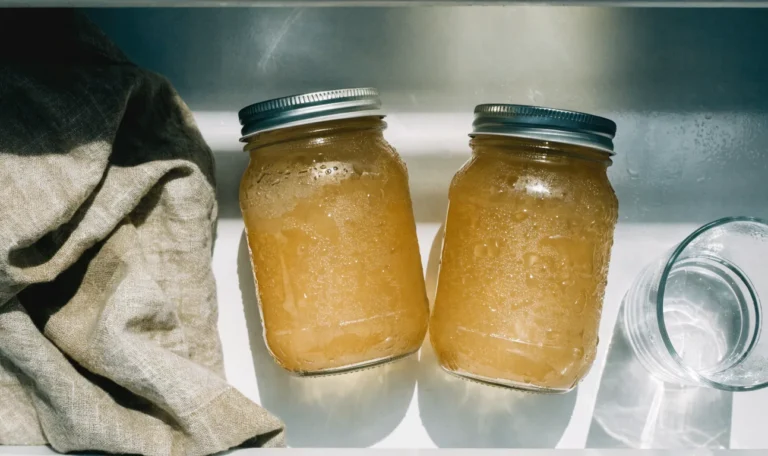 Two sealed glass mason jars of golden sea moss gel on a cool white refrigerator shelf, condensation on the glass, illustrating does sea moss expire.
