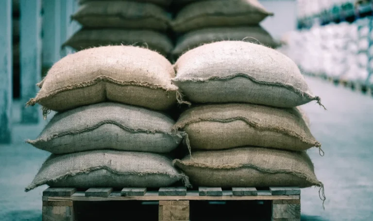 Stacked hessian sacks of dried sea moss on a wooden pallet in a warehouse