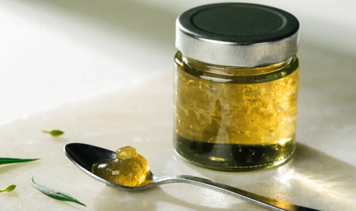 A small measured spoonful of golden sea moss gel beside a closed glass jar on a pale cream surface, restrained clinical styling, illustrating sea moss side effects.