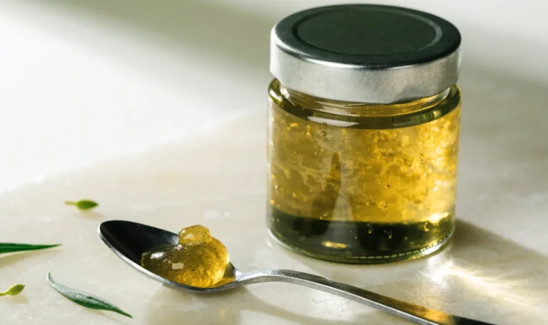 A small measured spoonful of golden sea moss gel beside a closed glass jar on a pale cream surface, restrained clinical styling, illustrating sea moss side effects.