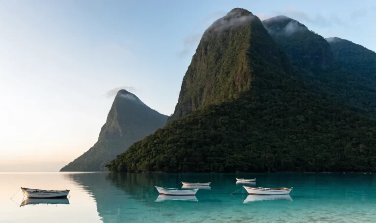 The Pitons rising above a calm bay on the west coast of Saint Lucia with small boats moored inshore