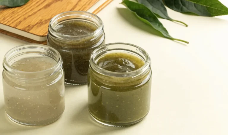 An unbranded flat lay comparing three plain glass jars of sea moss gel of different shades on a pale cream surface with a notebook, illustrating tailormade sea moss.